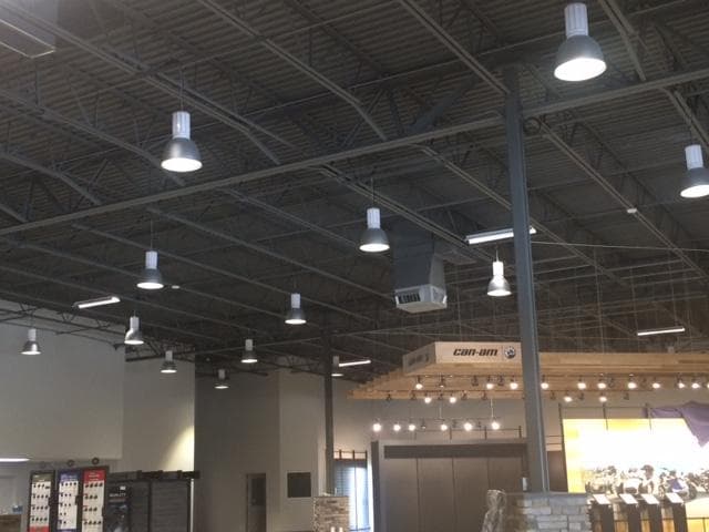 Interior of the Route 1 Motorsport sales showroom in Palm Bay, Florida, with exposed ceiling structure, high-bay lighting, HVAC equipment, and Can-Am retail displays.