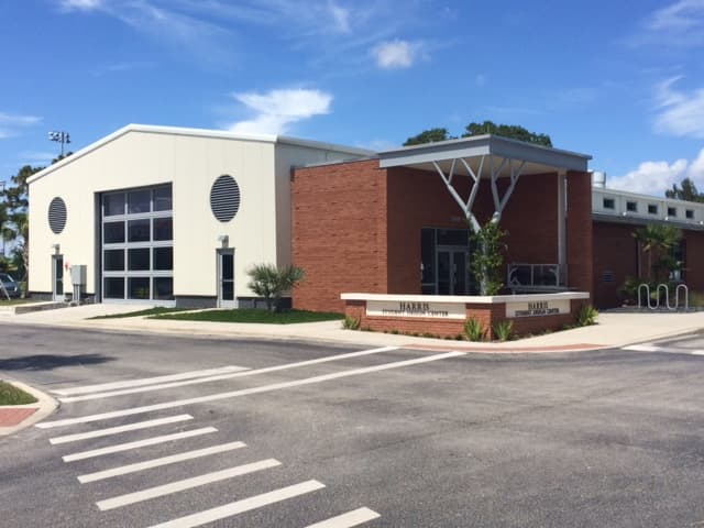 Exterior of the Harris Student Design Center at Florida Institute of Technology in Melbourne, Florida, with a cream metal workshop wing, red brick entrance, and monument sign.